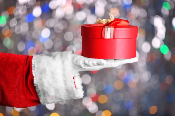 Concepto de Navidad. Santa Claus mano sosteniendo caja de regalo sobre fondo bokeh — Foto de Stock