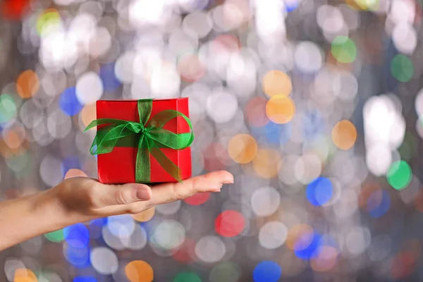 Χριστουγεννιάτικη ιδέα. Γυναικείο χέρι που κρατά το κουτί δώρου σε φόντο bokeh — Φωτογραφία Αρχείου