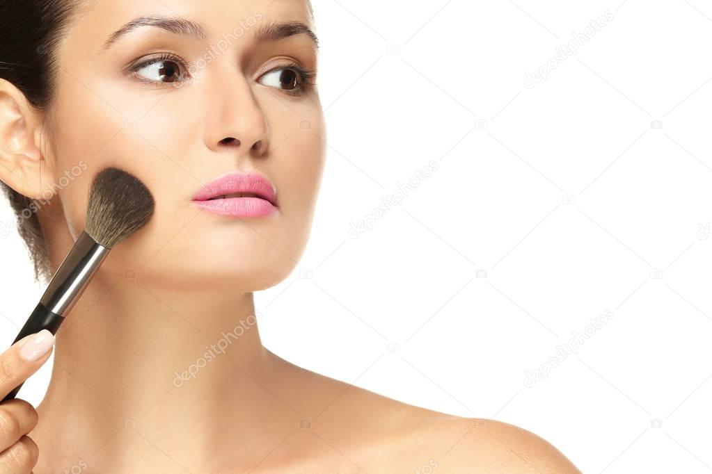 Beautiful girl applying cosmetics on white background