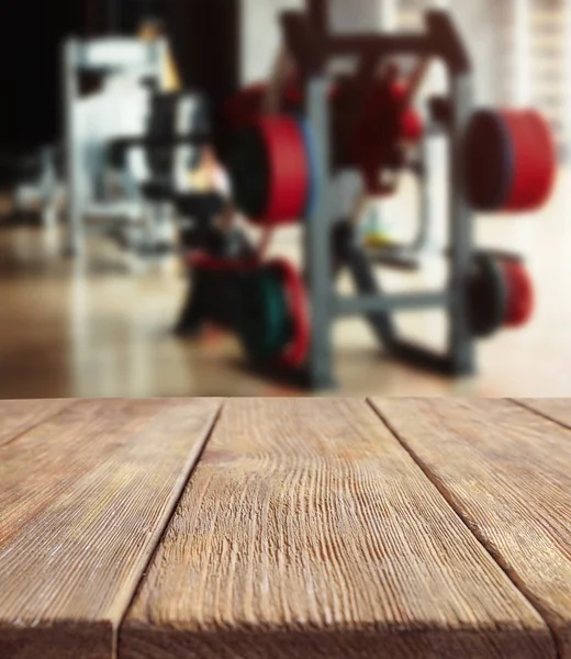 Wooden table against blurred gym interior background. Sport and healthcare concept.