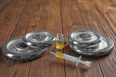Weight disks and syringe on wooden background clipart