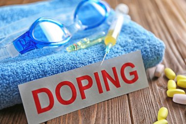 Sports equipment, word Doping and syringe on wooden background clipart