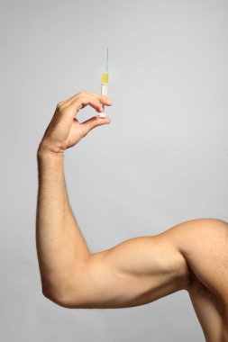 Sportsman hand holding syringe on light background clipart