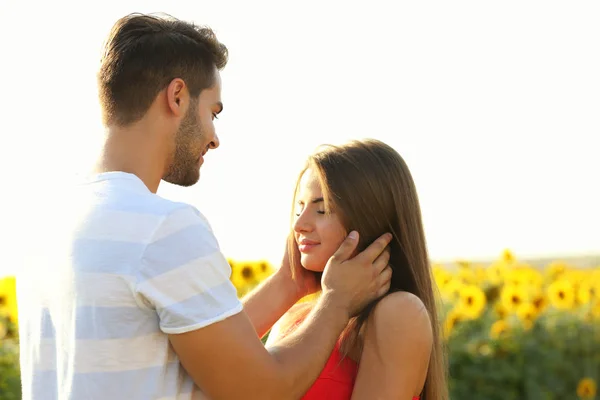 Romantische jong koppel omarmen in een veld met zonnebloemen — Stockfoto