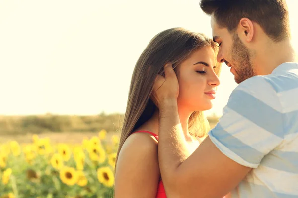 Schönes junges Paar umarmt sich in einem Feld von Sonnenblumen — Stockfoto