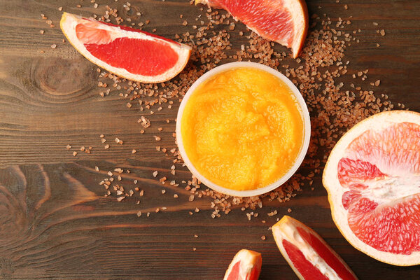 Скраб для тела и грейпфрут на деревянном фоне
