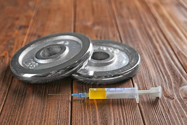 Weight disks and syringe on wooden background — Stock Photo, Image