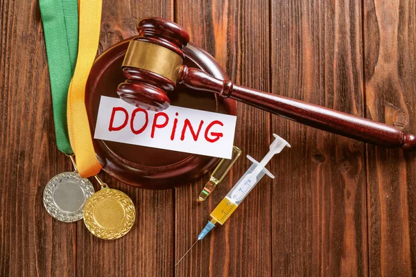 Martillo, palabra Doping y jeringa sobre fondo de madera — Foto de Stock