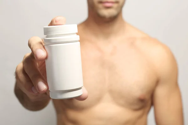 Homem muscular segurando drogas em garrafa, close-up — Fotografia de Stock