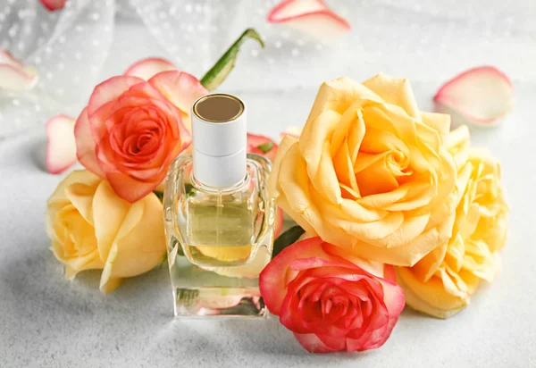 Composición de frasco de perfume y rosas sobre fondo claro — Foto de Stock