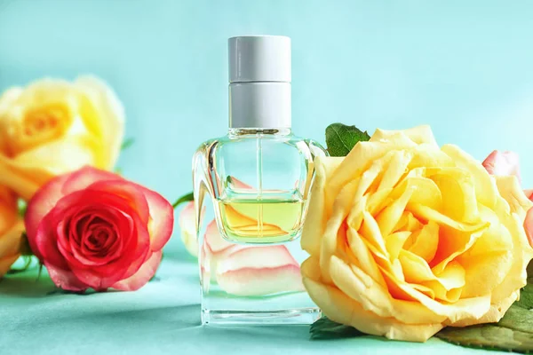 Composição de frascos de perfume e rosas sobre fundo de cor — Fotografia de Stock