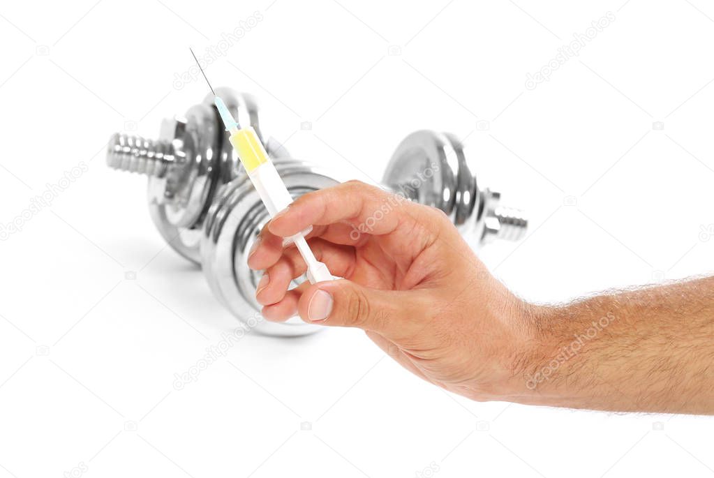 Male hand holding syringe and dumbbells on background