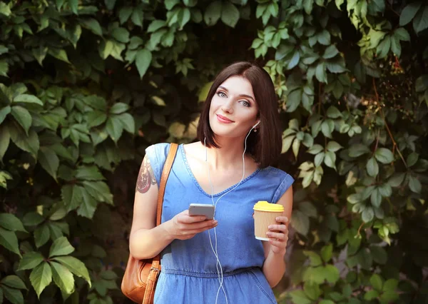Ung vacker flicka utomhus med telefon och kopp kaffe — Stockfoto