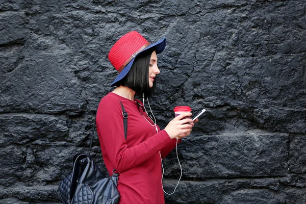 Vacker ung kvinna med telefon och kopp kaffe på mörk texturerat bakgrund — Stockfoto