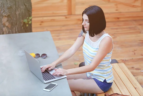 Hermosa mujer joven utilizando el ordenador portátil al aire libre — Foto de Stock