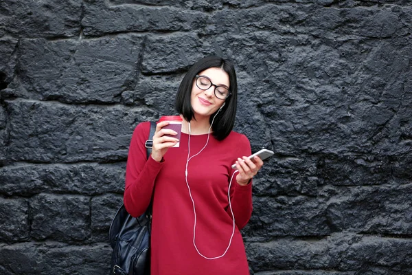 Vacker ung kvinna med telefon och kopp kaffe på mörk texturerat bakgrund — Stockfoto