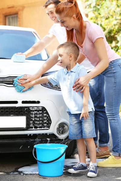 Happy family washing car on street