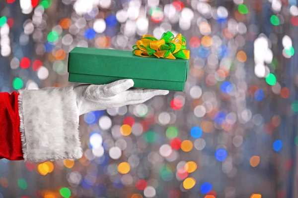 Kerst concept. Santa Claus hand met de doos van de gift op de achtergrond bokeh — Stockfoto