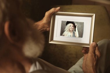 Yaşlı adam genç kadın resim ile fotoğraf çerçevesi tutarak. Mutlu anılar kavramı.