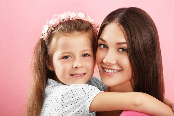 Niedliches Mädchen mit Mutter auf rosa Wandhintergrund — Stockfoto