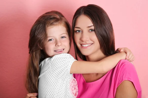 Niedliches Mädchen mit Mutter auf rosa Wandhintergrund — Stockfoto