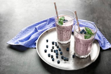 Lezzetli güler yüzlü, yaban mersini ve payet gri masada iki bardak ile tepsi