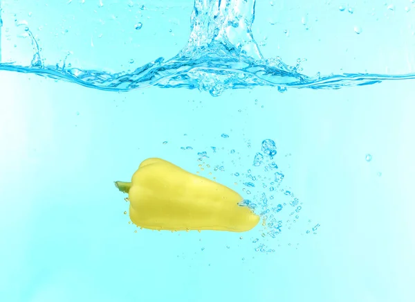Peppar faller in vatten på färgbakgrund — Stockfoto