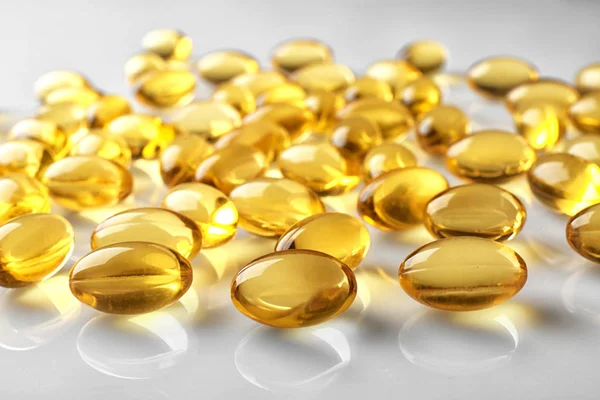 Capsules of fish oil on light background, close up view — Stock Photo, Image