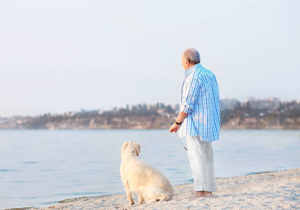 Старший мужчина и большая собака на берегу реки
