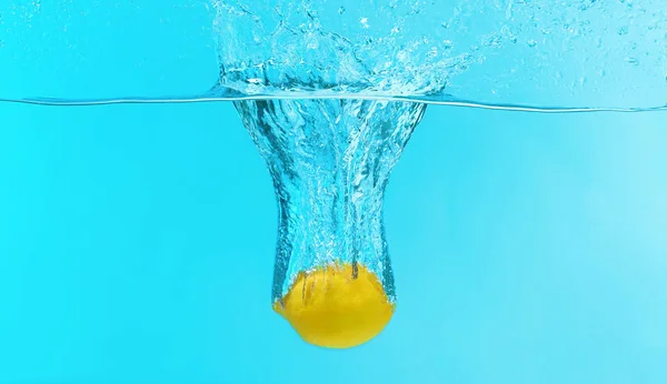 Citron tombant dans l'eau sur fond de couleur Photo De Stock