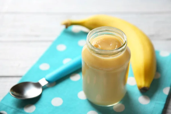 Glazen pot van baby puree met lepel op servet — Stockfoto