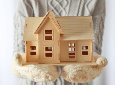 Kadın eldivenler kontrplak oyuncak ev tutarak ellerinde