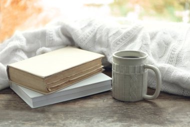 Kitap ve ekose pencere üzerinde sıcak içecekle