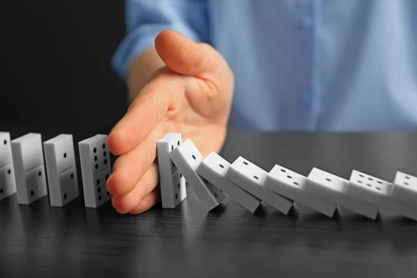 Businesswoman hand trying to stop toppling dominoes on table — Stock Photo, Image