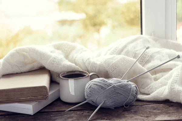 Hot drink with books, threads and plaid on windowsill — Stock Photo, Image