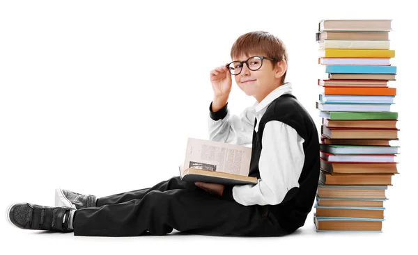 Carino scolaro seduto accanto mucchio di libri su sfondo bianco — Foto Stock