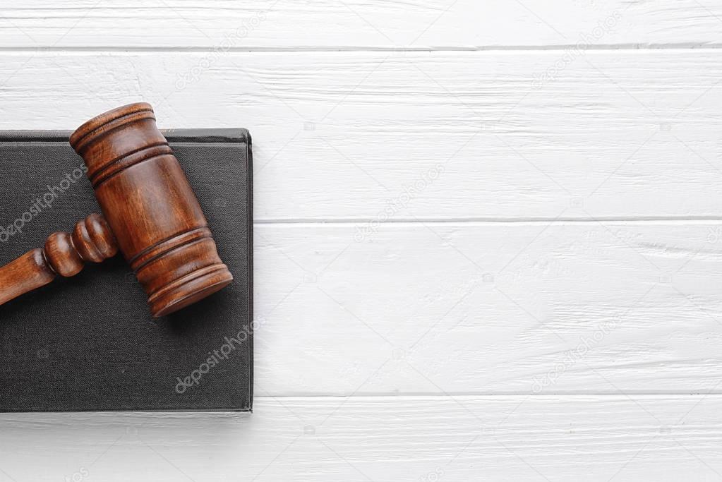 Gavel and book on wooden background, top view