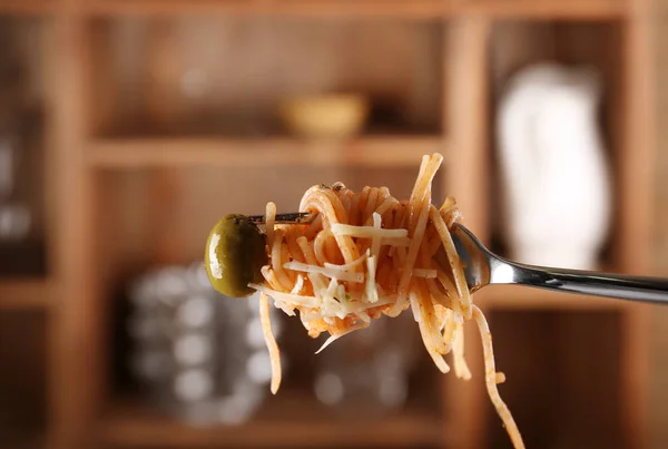 Pasta på gaffel med oliven på utydelig bakgrunn – stockfoto