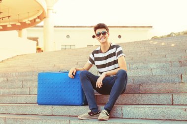 Merdivenlerde oturan büyük mavi gövde ile genç adam