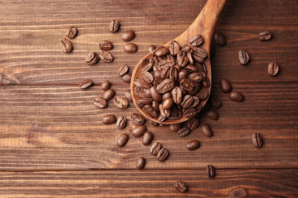 Sendok kayu dan biji kopi pada latar belakang kayu — Stok Foto