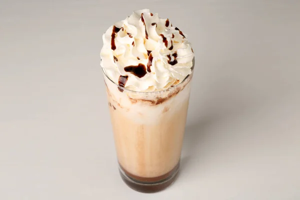 Vaso de delicioso batido de leche con crema batida y cobertura de chocolate sobre fondo claro — Foto de Stock