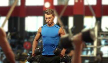 Spor salonunda dambıllarla atletizm antrenmanı