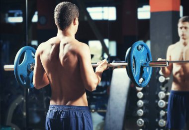 Spor salonunda halterli adam eğitimi.