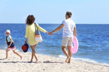 Mutlu bir aile sahilde yürüyor.