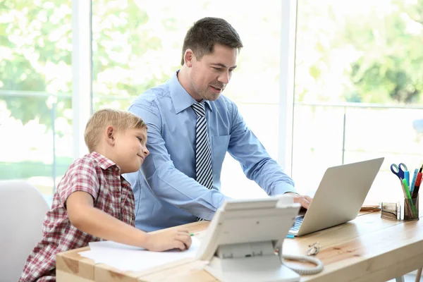 Little boy and father working at office