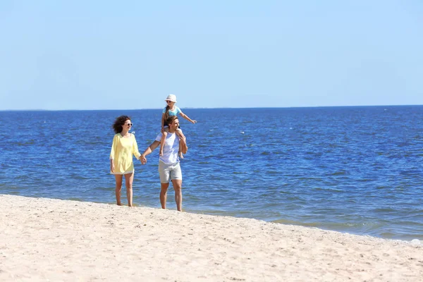 Familienkonzept. Eltern mit Tochter spazieren am Strand — Stockfoto