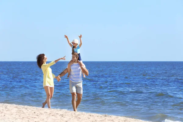 Concepto familiar. Padres con hija caminando por la playa — Foto de Stock