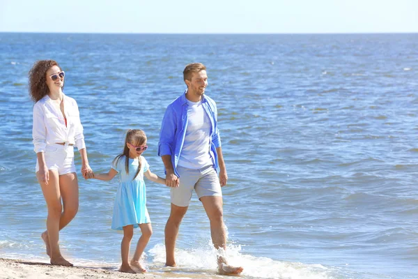 Concepto familiar. Padres con hija tomados de la mano y caminando en la orilla del mar — Foto de Stock