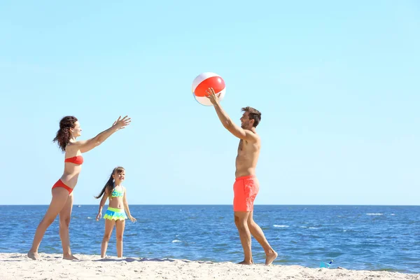 Concetto familiare. Genitori e figlia che giocano con la palla sulla spiaggia — Foto Stock