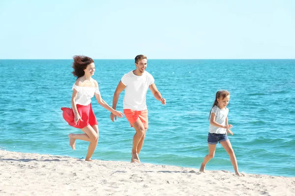 Familienkonzept. glückliche Eltern und Tochter spielen am Strand — Stockfoto